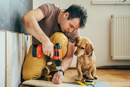Man working on his home with dog by his side
